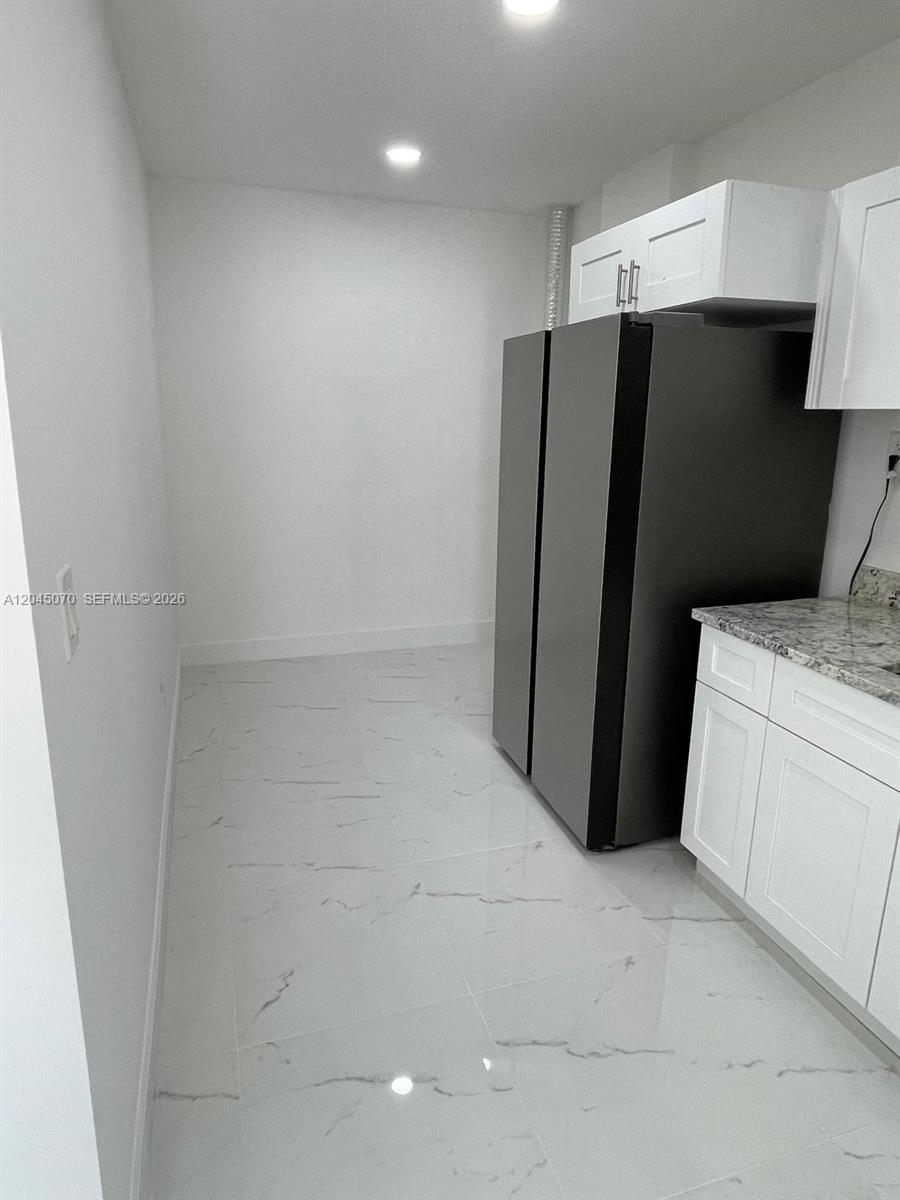 A kitchen area features white cabinets, a dark refrigerator, and white marble-patterned tile flooring — 15975 SW 109th St # 1, Miami FL 33196, MIAMI, FL