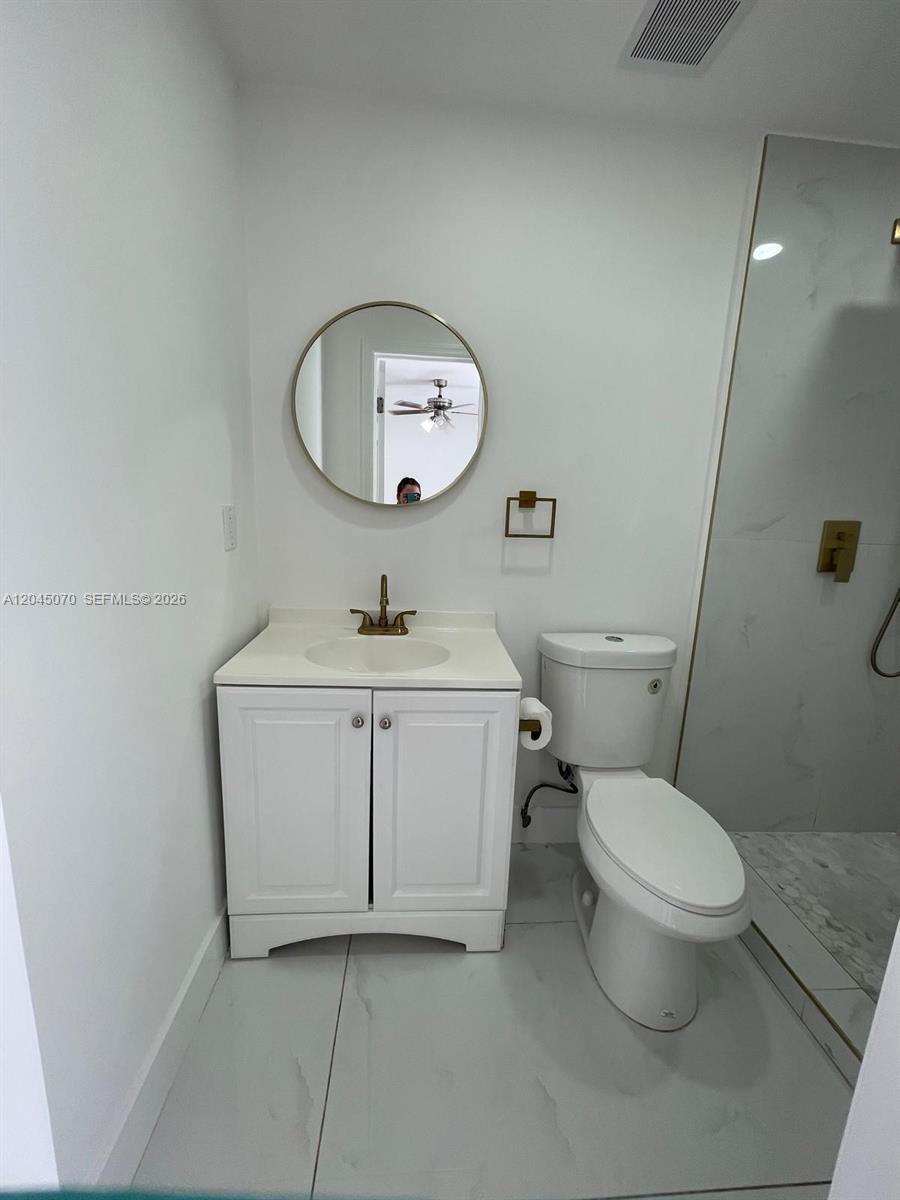 A small bathroom features a white vanity, a round mirror, and a glass-enclosed shower — 15975 SW 109th St # 1, Miami FL 33196, MIAMI, FL