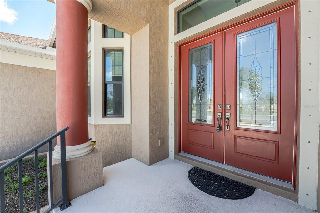 A red double front door with glass inserts sits on a concrete porch with columns — 174 ROTONDA BOULEVARD E, ROTONDA WEST, FL