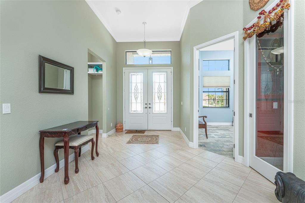 A bright entryway features light green walls, tile flooring, a console table, and double front doors — 174 ROTONDA BOULEVARD E, ROTONDA WEST, FL