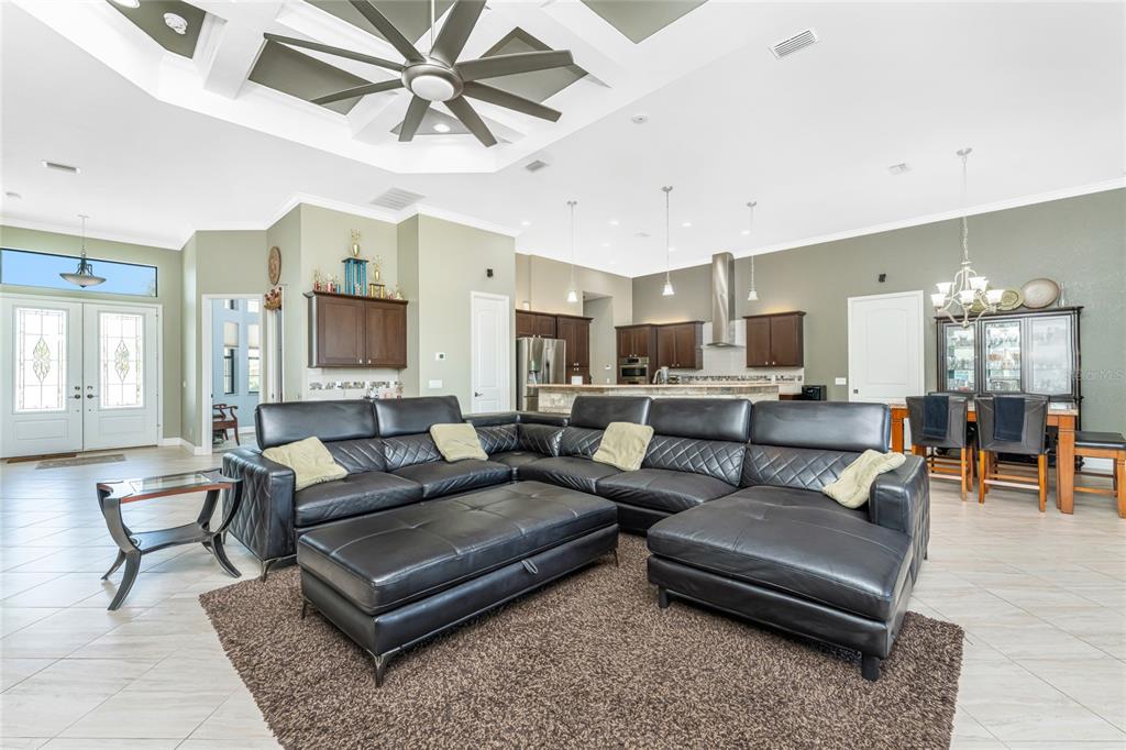 A spacious open-concept living room features a large black sectional sofa and a kitchen area — 174 ROTONDA BOULEVARD E, ROTONDA WEST, FL