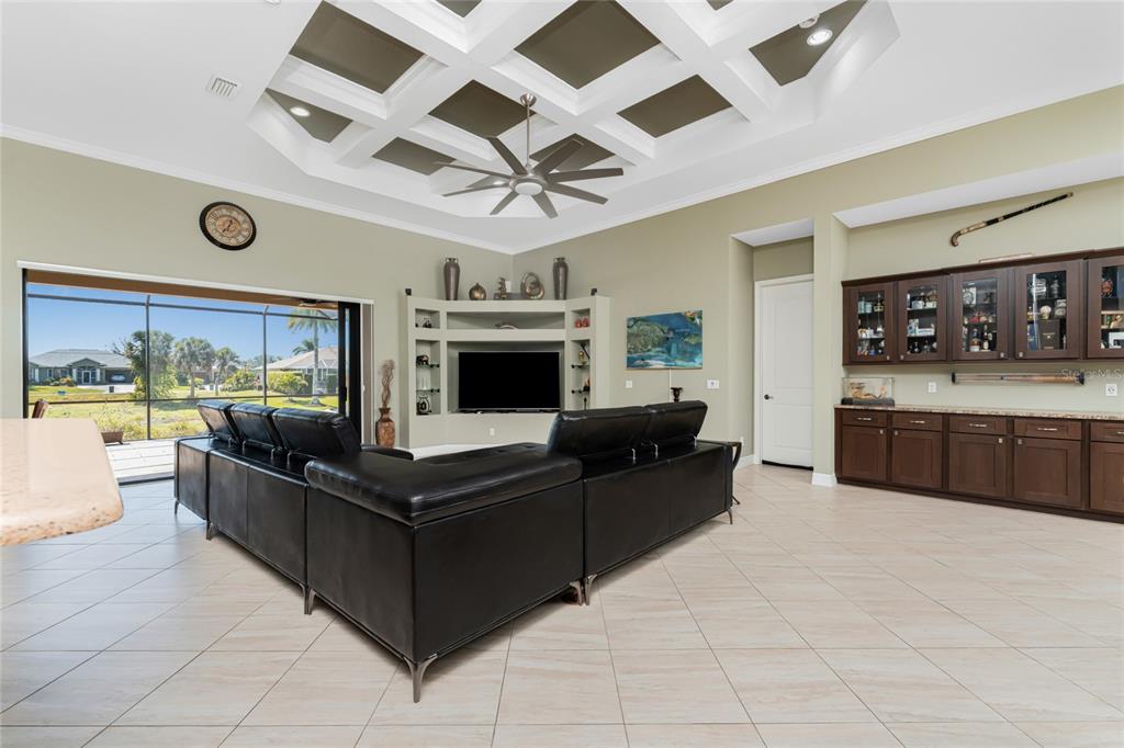 A living room features a coffered ceiling, a large sectional sofa, and built-in cabinetry — 174 ROTONDA BOULEVARD E, ROTONDA WEST, FL