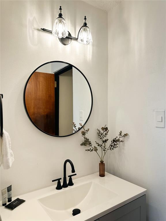 A bathroom vanity features a round black-framed mirror, a black faucet, and a wall-mounted light — bloque 24 CALLE JOSE SEVERO QUINONEZ, CAROLINA, PR