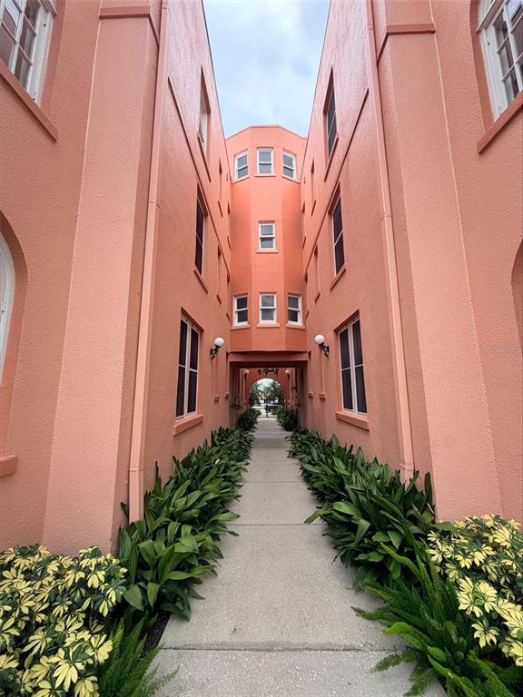 A concrete walkway leads between two salmon-colored apartment buildings toward an arched passageway — 1221 N PALM AVENUE UNIT 204, SARASOTA, FL