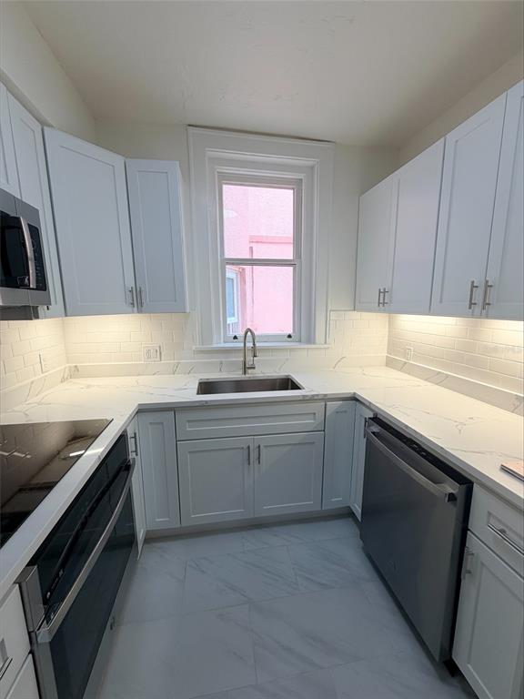A galley kitchen features white cabinets, marble-look countertops, a stainless steel sink, and tile flooring — 1221 N PALM AVENUE UNIT 204, SARASOTA, FL