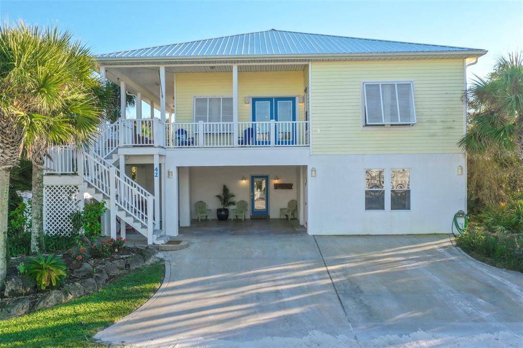 A two-story elevated house with a concrete driveway, a covered ground-level patio, and a balcony — 42 MOODY DRIVE, PALM COAST, FL