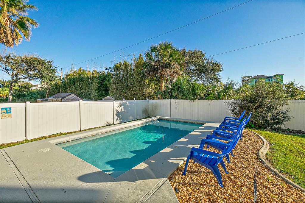 A rectangular swimming pool sits in a backyard with blue chairs and a white fence — 42 MOODY DRIVE, PALM COAST, FL