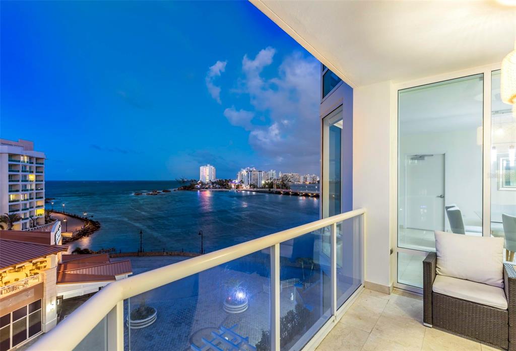 A balcony with a glass railing overlooks a coastal city skyline at twilight — 5 MUNOZ RIVERA AVENUE UNIT 504, SAN JUAN, PR