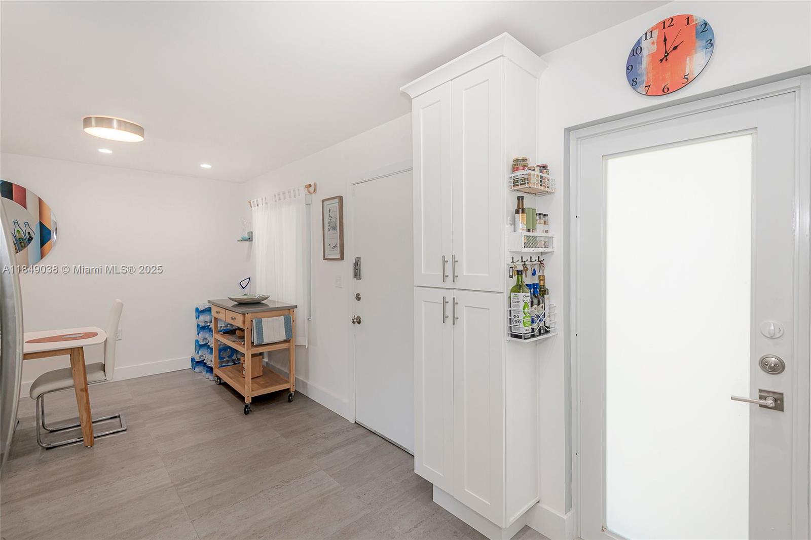A bright room features white cabinetry, a rolling kitchen cart, and a glass-paneled door — 1631 NE 114th St # 112, Miami FL 33181, MIAMI, FL