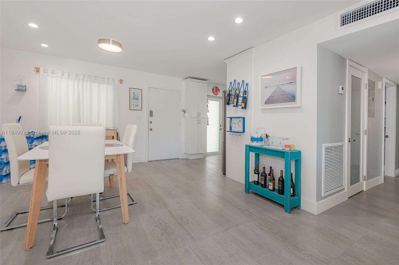 A dining area with a white table and chairs sits next to a turquoise console table — 1631 NE 114th St # 112, Miami FL 33181, MIAMI, FL