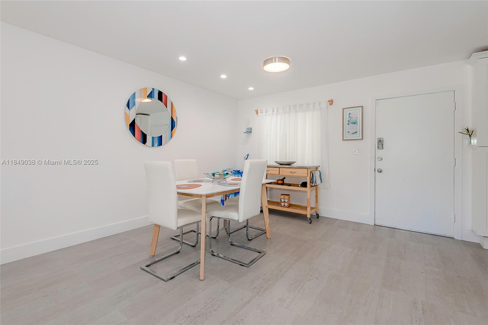 A dining area features a white table with four chairs, a rolling cart, and a mirror — 1631 NE 114th St # 112, Miami FL 33181, MIAMI, FL