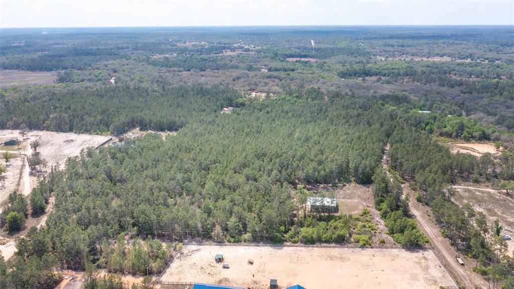 An aerial view shows a large, wooded property with a house and open sandy areas — 5276 ORGANIC. (POLE BARN) ROAD, MELROSE, FL