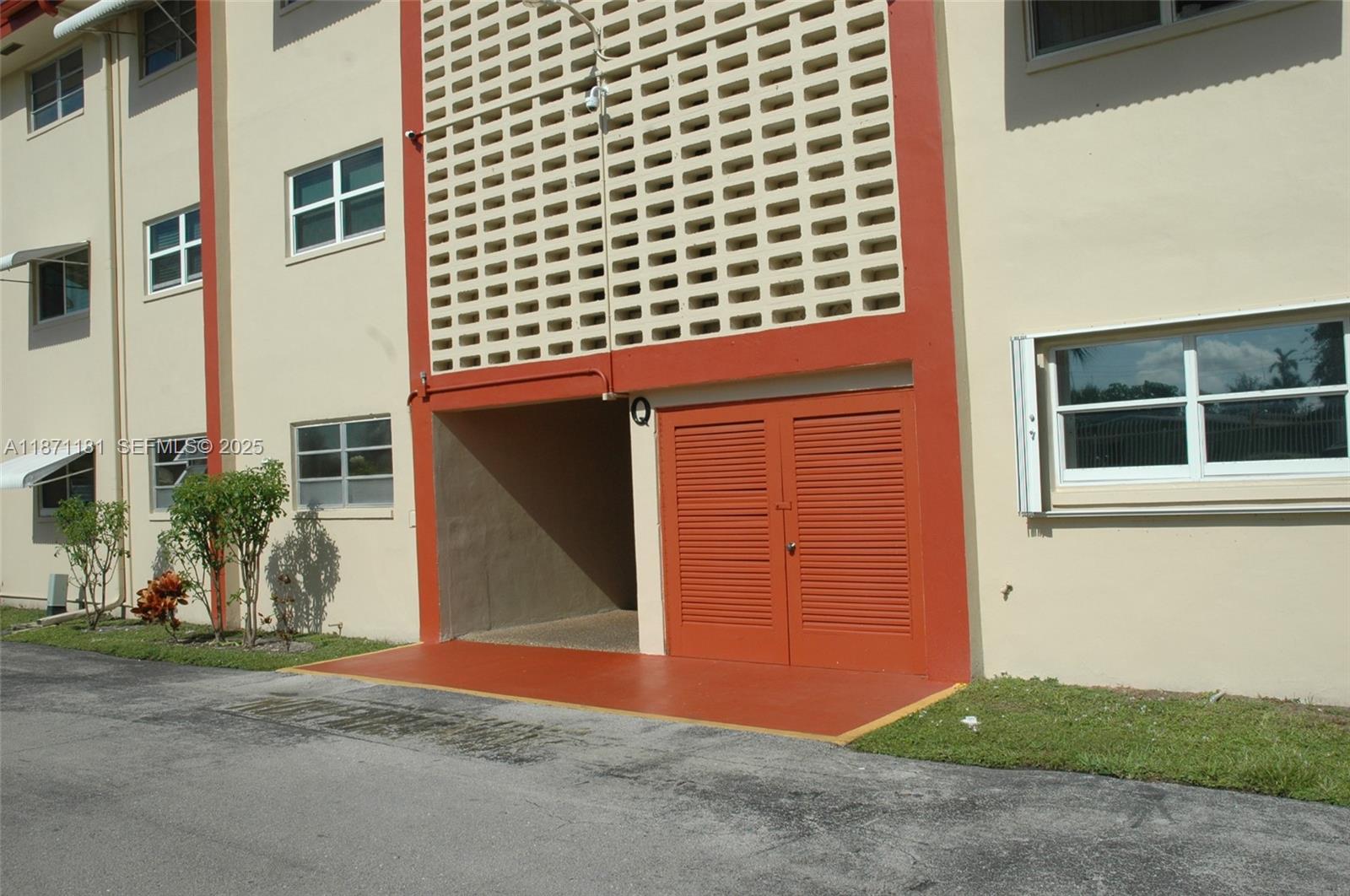 The exterior of a multi-story apartment building features a ground-level storage area with louvered doors — 5300 Washington St # Q307, Hollywood FL 33021, HOLLYWOOD, FL