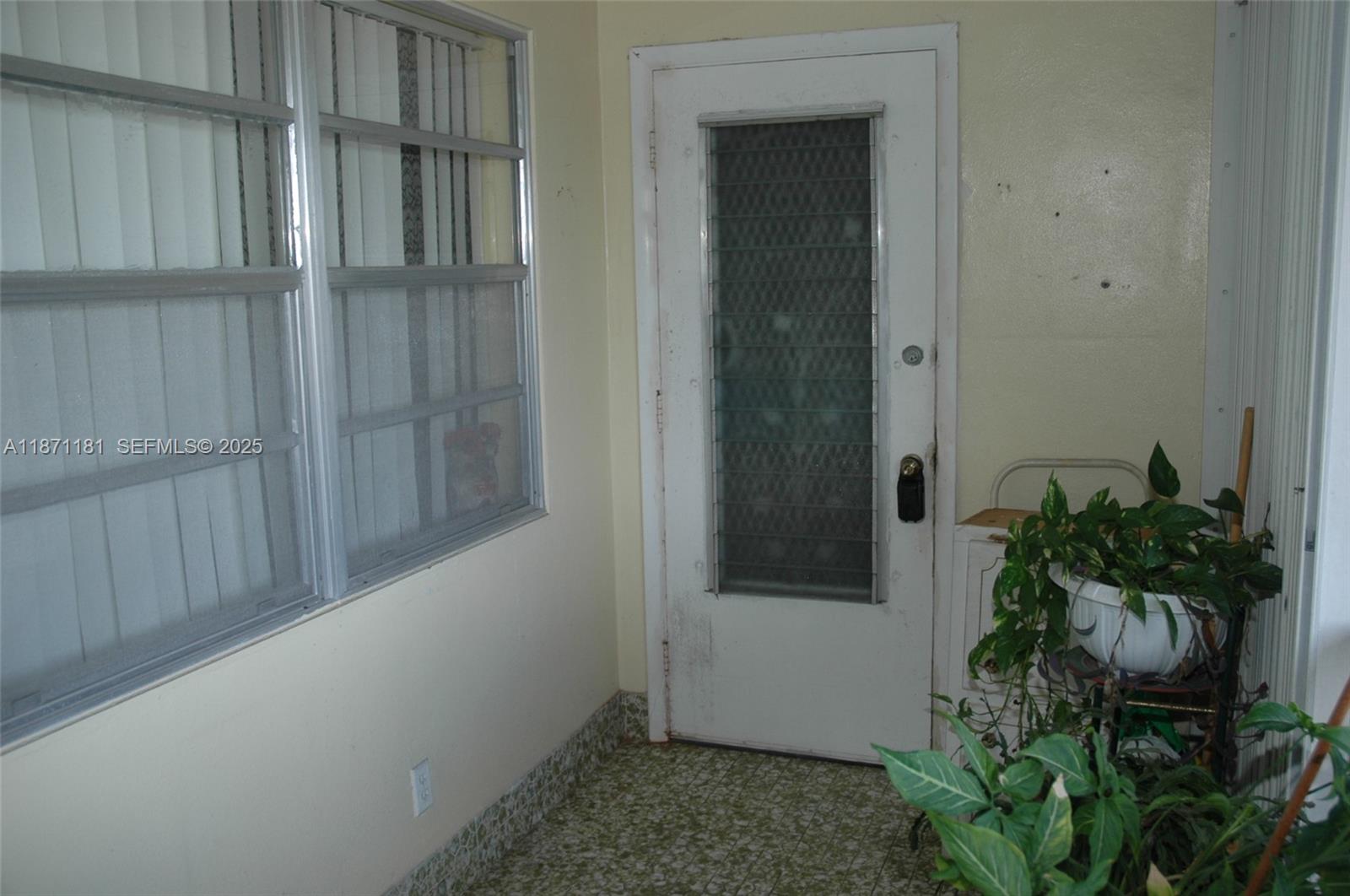 A white door with a jalousie window sits beside a window in a small room — 5300 Washington St # Q307, Hollywood FL 33021, HOLLYWOOD, FL