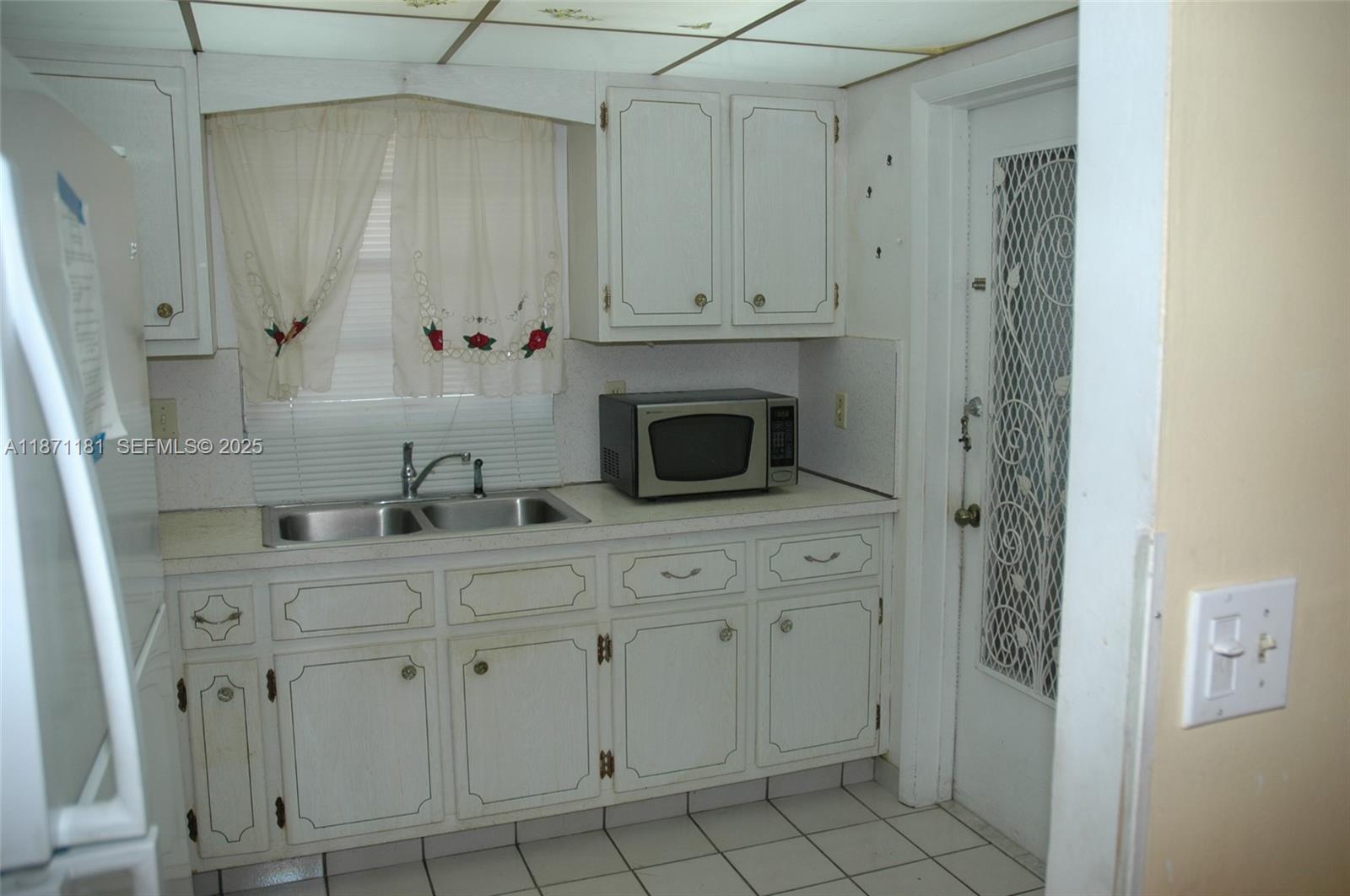A kitchen features white cabinets, a double sink, a microwave, and a tiled floor — 5300 Washington St # Q307, Hollywood FL 33021, HOLLYWOOD, FL