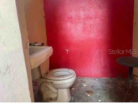 A bathroom with a toilet, a pedestal sink, and a bright red painted wall — Km. 5.0 ,PR-486, ABRA HONDA ROAD, CAMUY, PR