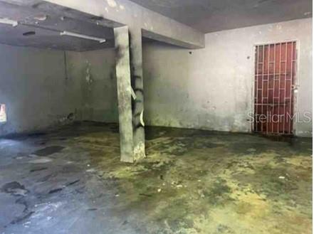 An unfinished, dimly lit concrete room with a support pillar and a metal security gate — Km. 5.0 ,PR-486, ABRA HONDA ROAD, CAMUY, PR