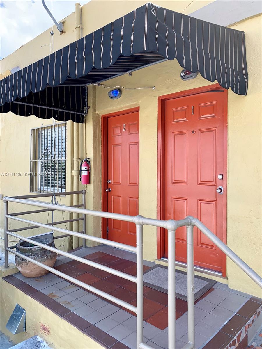 Two orange doors with numbers are situated under a striped awning on a porch — 173 NW 36th St # 2, Miami FL 33127, MIAMI, FL