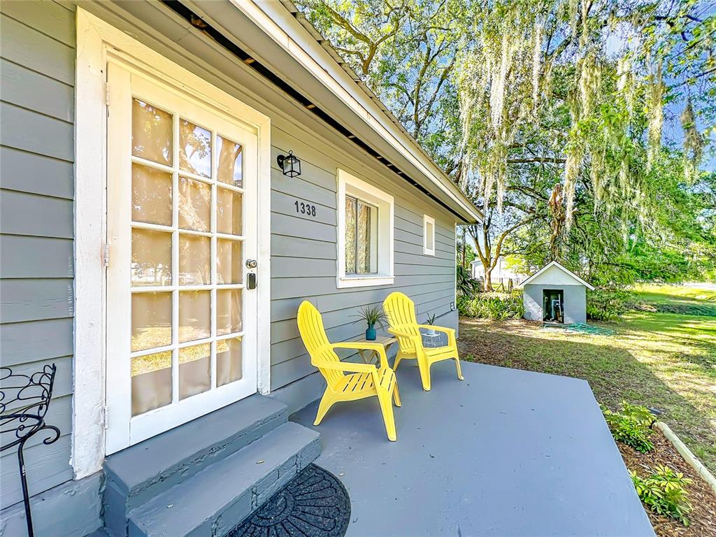 A gray house exterior features a white-framed glass door, two yellow chairs, and a porch — 1338 SAINT NICHOLAS AVENUE, CHRISTMAS, FL