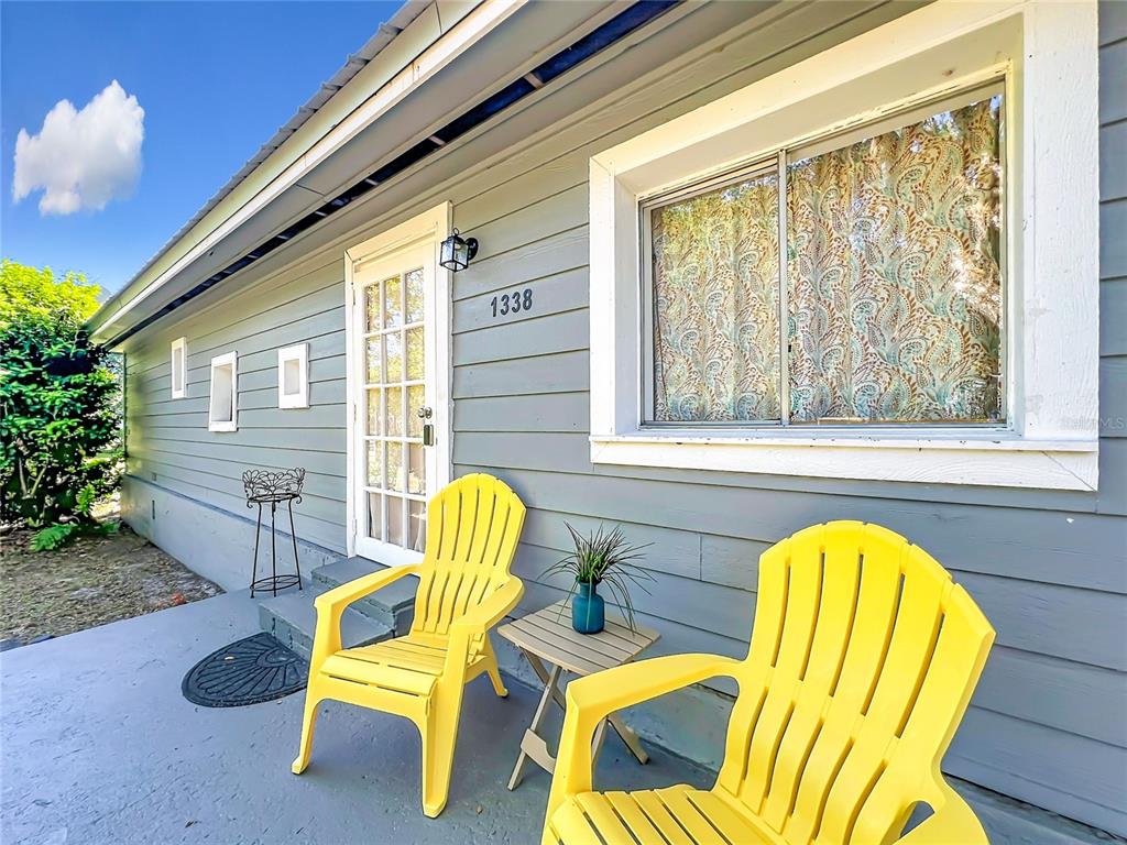 Two yellow chairs sit on a porch in front of a gray house with siding — 1338 SAINT NICHOLAS AVENUE, CHRISTMAS, FL