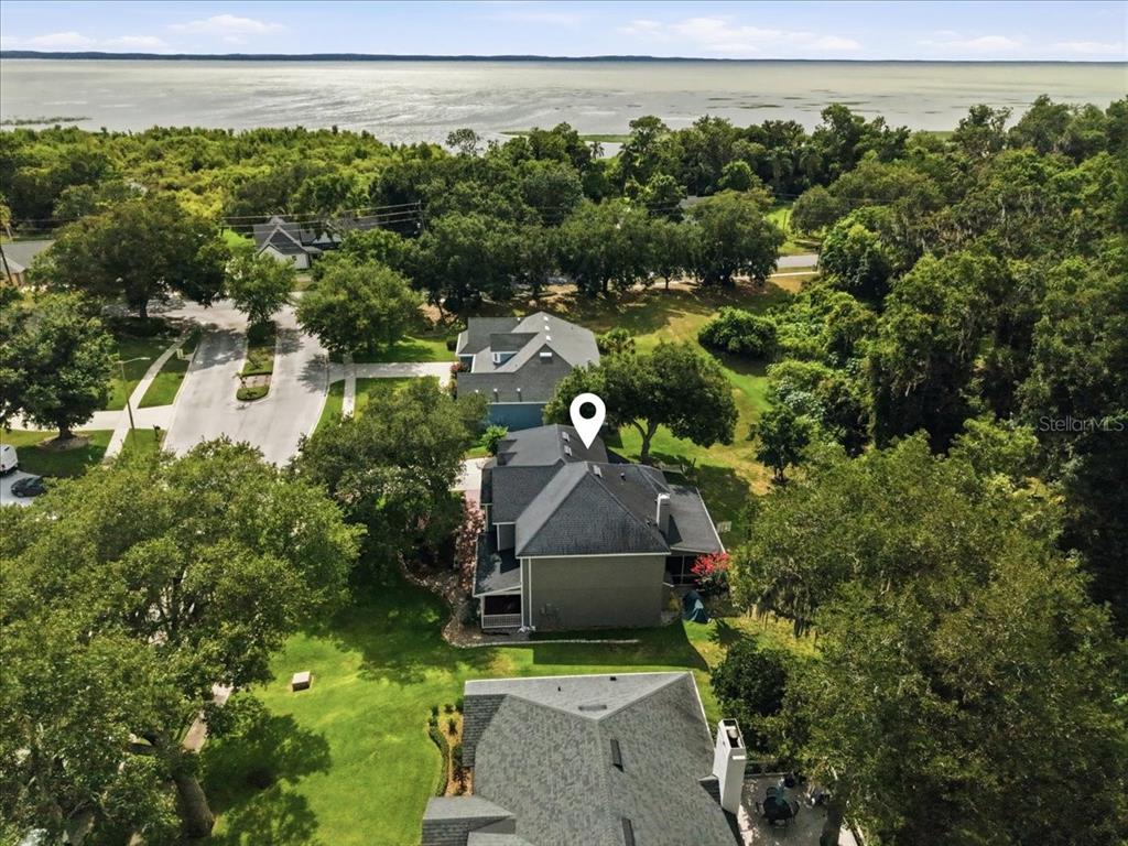 An aerial view shows a house with a dark roof surrounded by trees near water — 519 TEAGARDEN COURT, WINTER GARDEN, FL