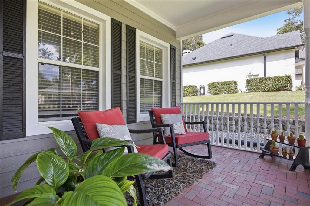 A covered porch features two red rocking chairs, a potted plant, and a small cactus stand — 519 TEAGARDEN COURT, WINTER GARDEN, FL