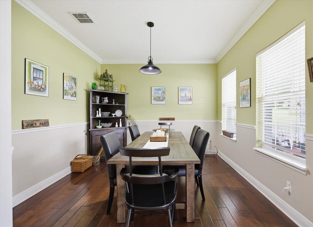 A dining room features a wooden table, black chairs, a hutch, and two-toned walls — 519 TEAGARDEN COURT, WINTER GARDEN, FL