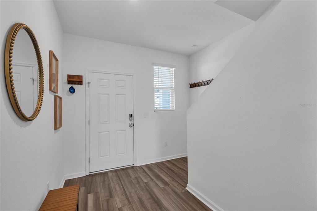 An entryway features a white door, wood-look flooring, a gold-framed mirror, and a staircase — 6359 KAY MORGAN LANE, GIBSONTON, FL