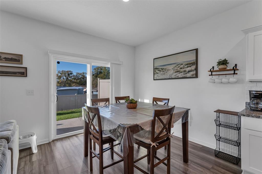 A dining area features a square table, four chairs, a sliding glass door, and wall art — 6359 KAY MORGAN LANE, GIBSONTON, FL