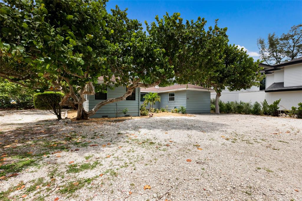 A light blue, single-story house with a gravel driveway and large trees in the yard — 103 51ST STREET, HOLMES BEACH, FL