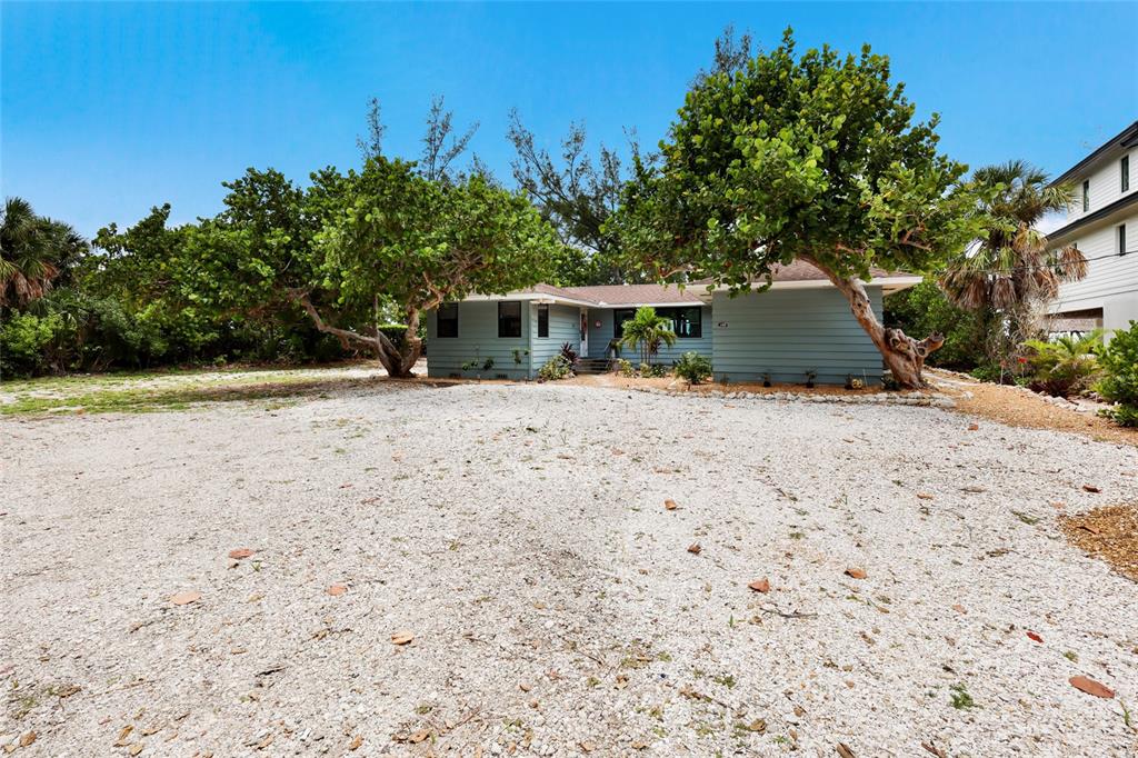 A light blue single-story house sits behind a large gravel driveway with two large trees — 103 51ST STREET, HOLMES BEACH, FL