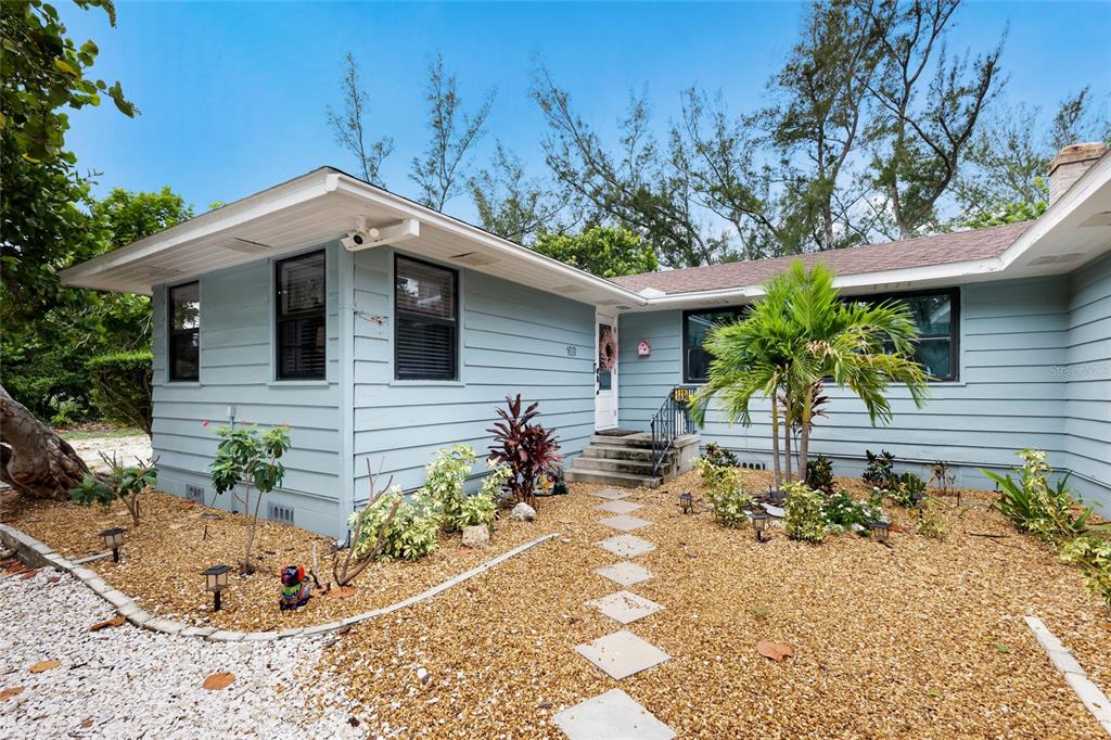 A light blue, single-story house features a gravel front yard with a stone walkway — 103 51ST STREET, HOLMES BEACH, FL