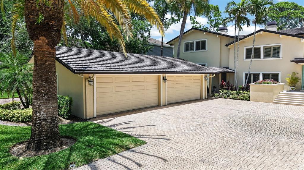 A beige house with a three-car garage and a large brick-paved driveway — 6305 BURNING TREE DRIVE, SEMINOLE, FL