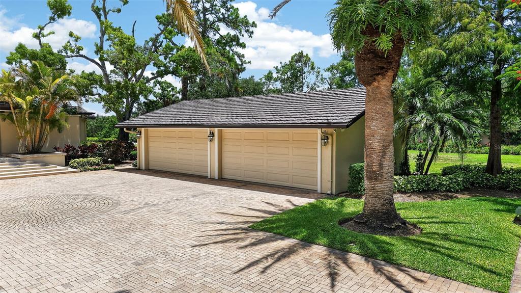 A detached two-car garage with a shingled roof sits beside a paved driveway and lawn — 6305 BURNING TREE DRIVE, SEMINOLE, FL