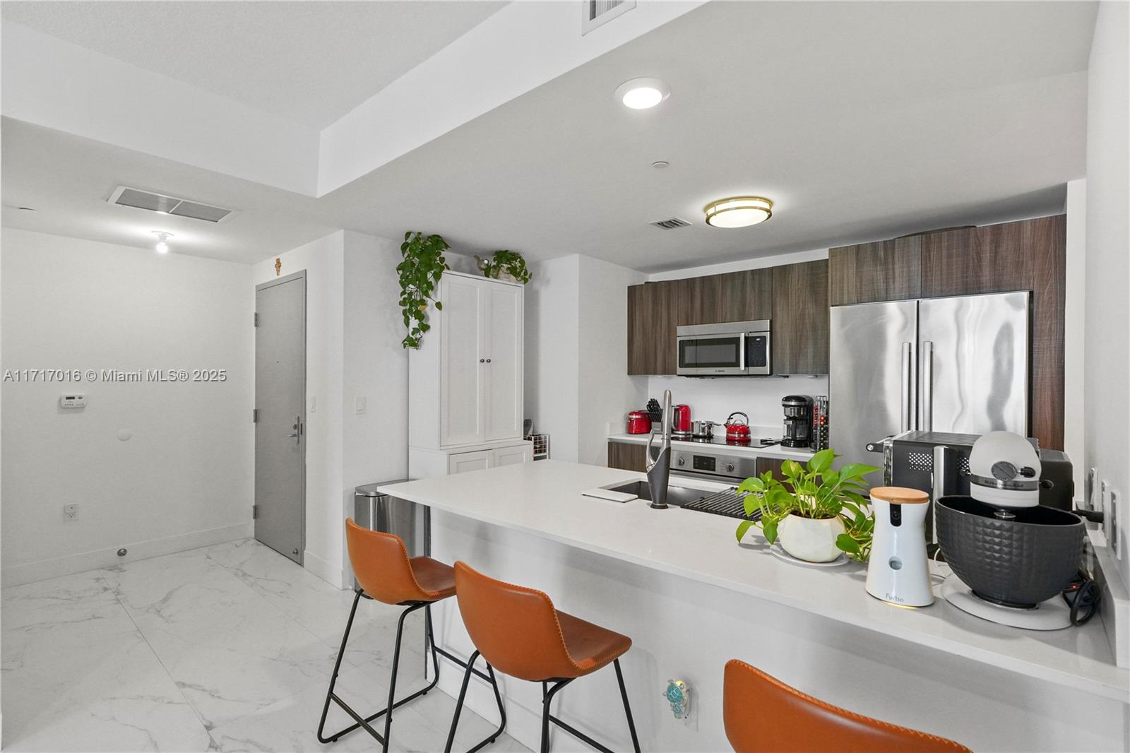 A modern kitchen features white countertops, dark wood cabinetry, and three orange bar stools — 488 NE 18th St # 4009, Miami FL 33132, MIAMI, FL