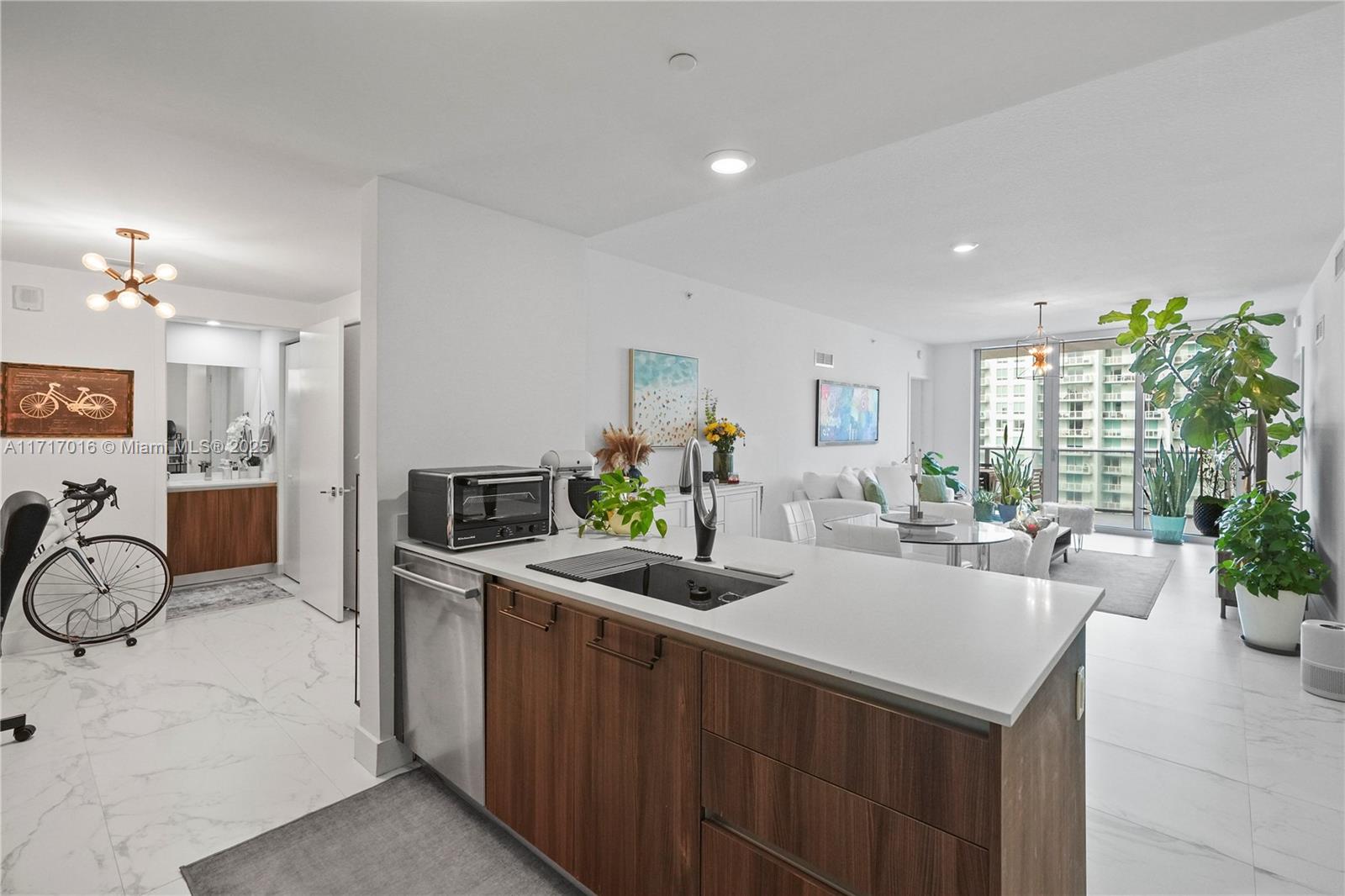 A modern kitchen island with wood cabinets and white countertops overlooks an open living area — 488 NE 18th St # 4009, Miami FL 33132, MIAMI, FL
