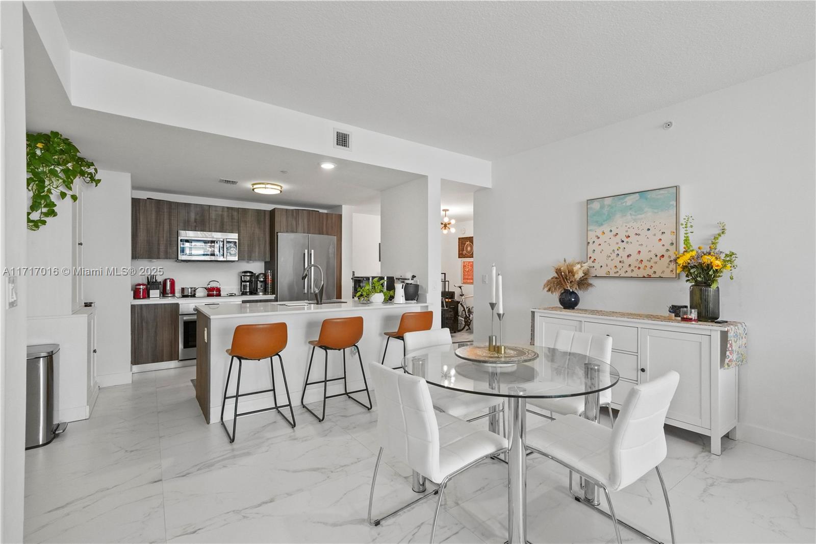 A modern kitchen with a breakfast bar and dining area features white marble-style flooring — 488 NE 18th St # 4009, Miami FL 33132, MIAMI, FL