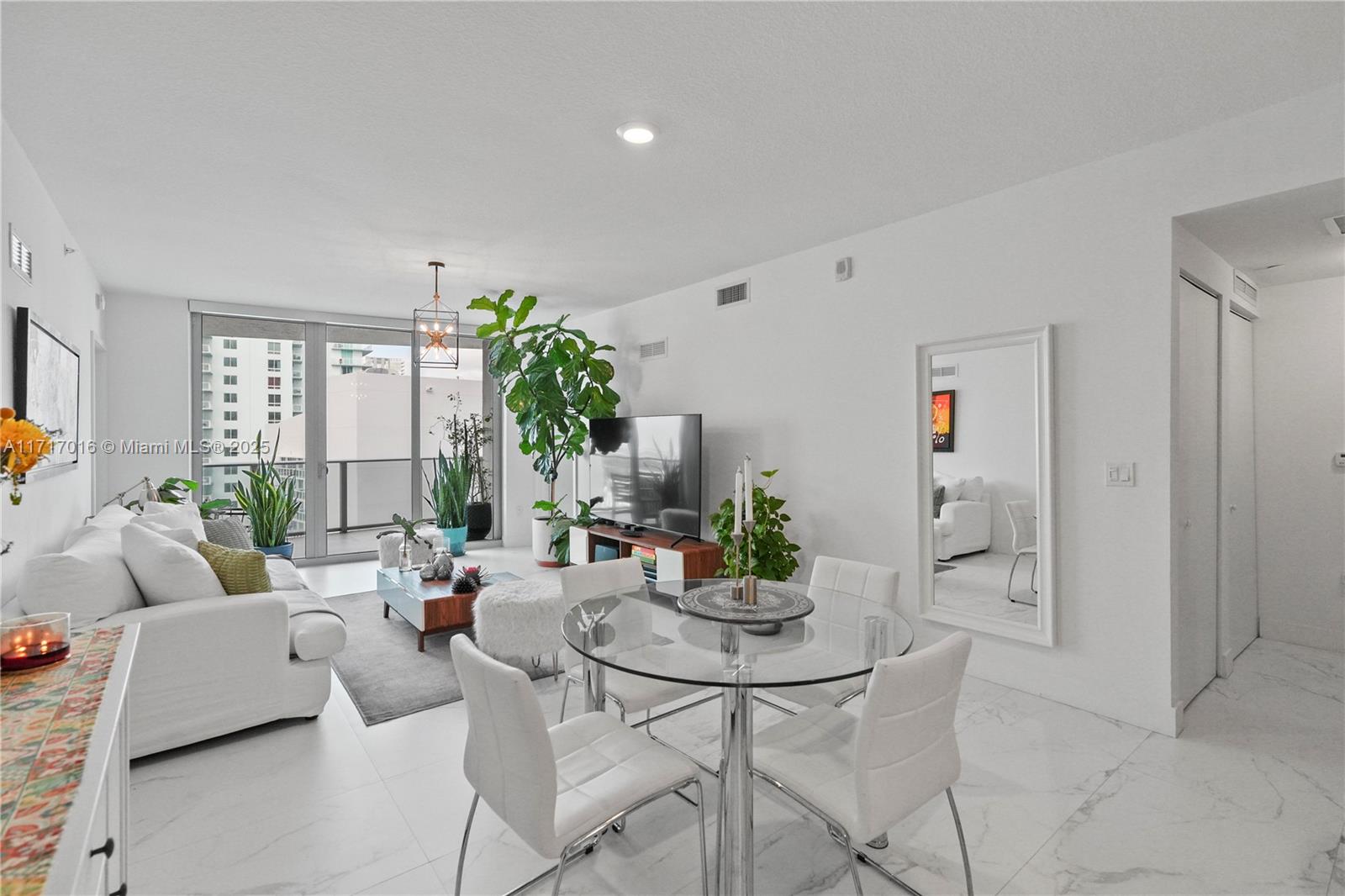 A bright living and dining area features white tile floors, a glass table, and balcony access — 488 NE 18th St # 4009, Miami FL 33132, MIAMI, FL
