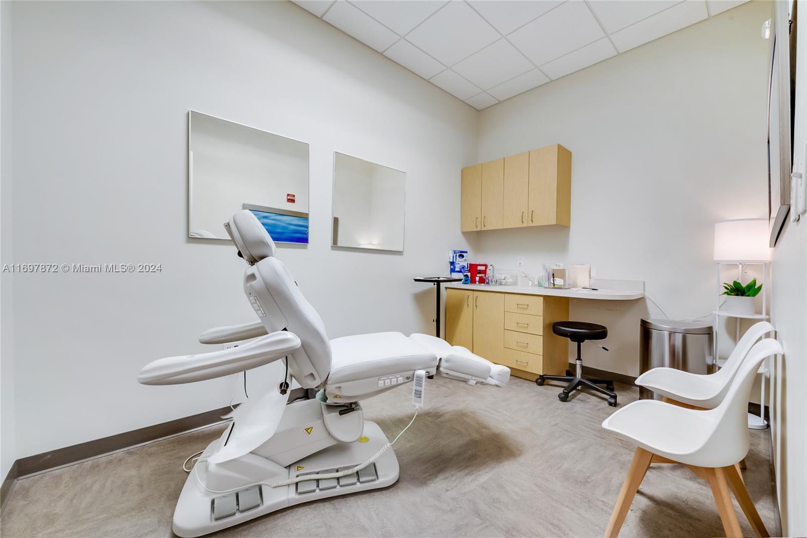 A medical examination room features a white procedure chair, light wood cabinetry, and two chairs — 6705 Red Rd # 518, Coral Gables FL 33143, CORAL GABLES, FL