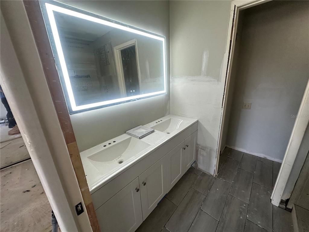 A kitchen with white cabinets, stainless steel appliances, and wood-look flooring opens to a living area — 717 OAK PARK PLACE, BRANDON, FL