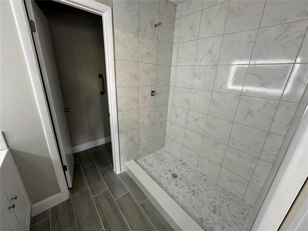 A kitchen features white cabinets, stainless steel appliances, and wood-look flooring near a white door — 717 OAK PARK PLACE, BRANDON, FL
