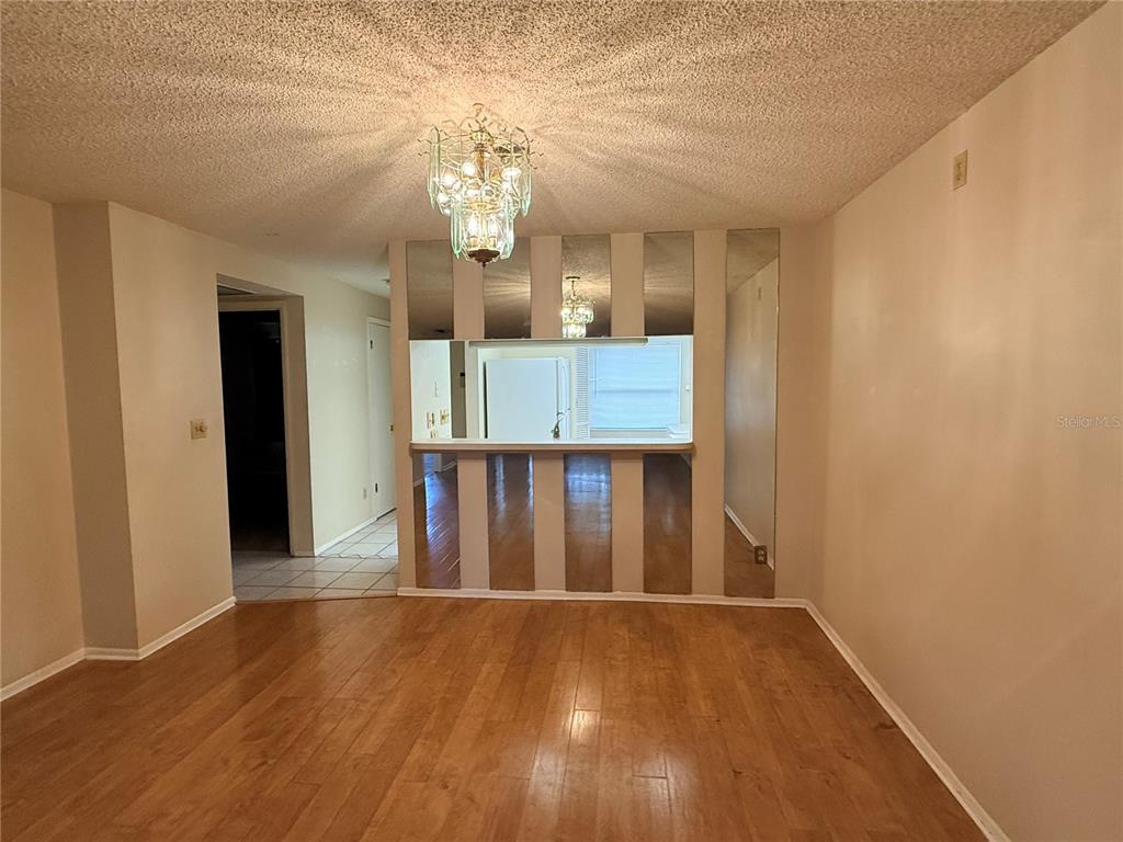 A dining area features wood flooring, a crystal chandelier, and a mirrored wall partition — 3832 TEESIDE DRIVE UNIT 4, NEW PORT RICHEY, FL
