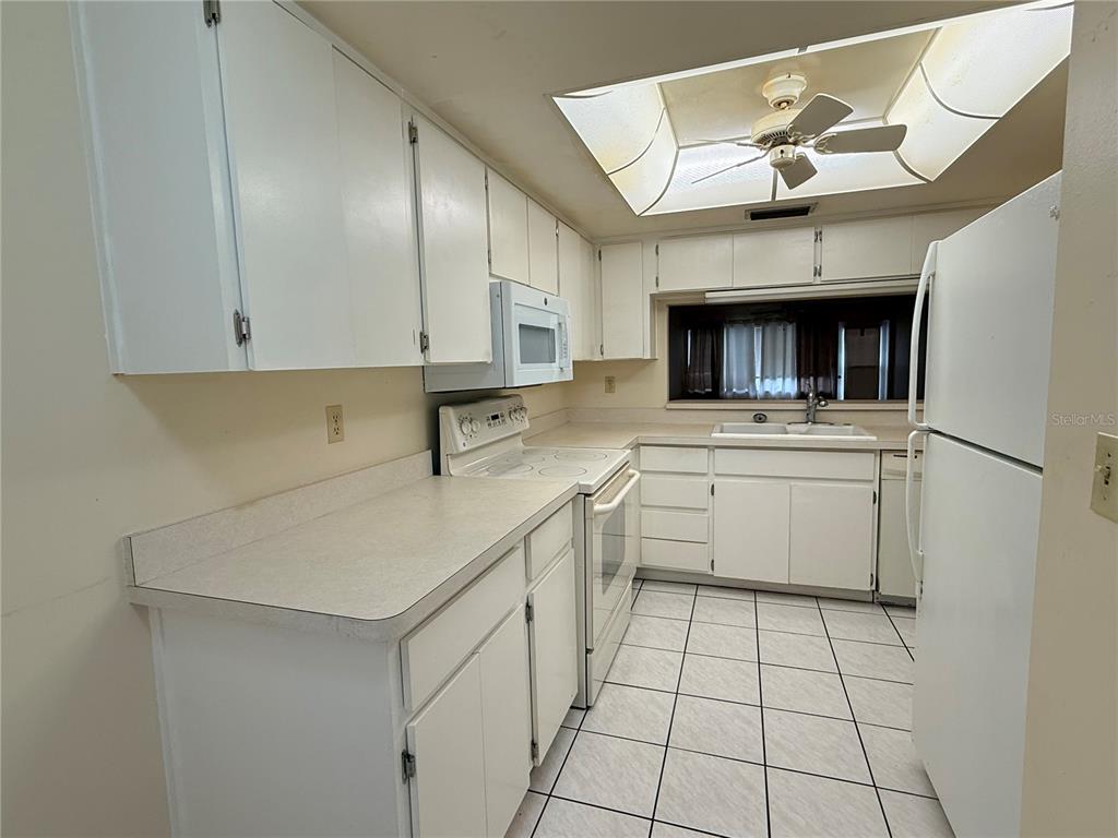 A kitchen features white cabinets, white appliances, laminate countertops, and tiled flooring — 3832 TEESIDE DRIVE UNIT 4, NEW PORT RICHEY, FL