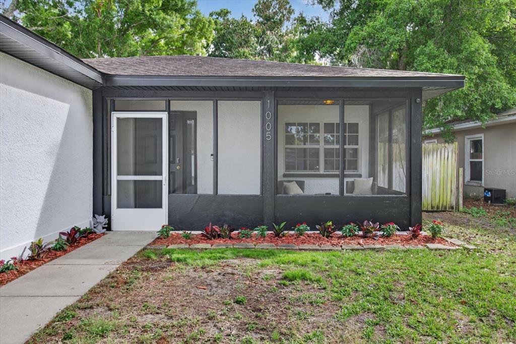 A screened-in front porch features black framing, white walls, and a concrete walkway — 1005 13TH AVENUE NW, LARGO, FL