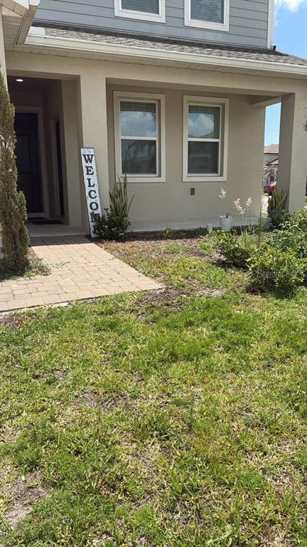 A view of a house exterior featuring a front porch, walkway, and a welcome sign — 6267 LAKEPINE STREET, ST CLOUD, FL