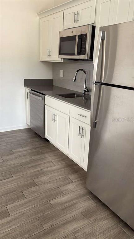 A kitchen features white cabinets, stainless steel appliances, a grey countertop, and wood-look tile flooring — 6267 LAKEPINE STREET, ST CLOUD, FL