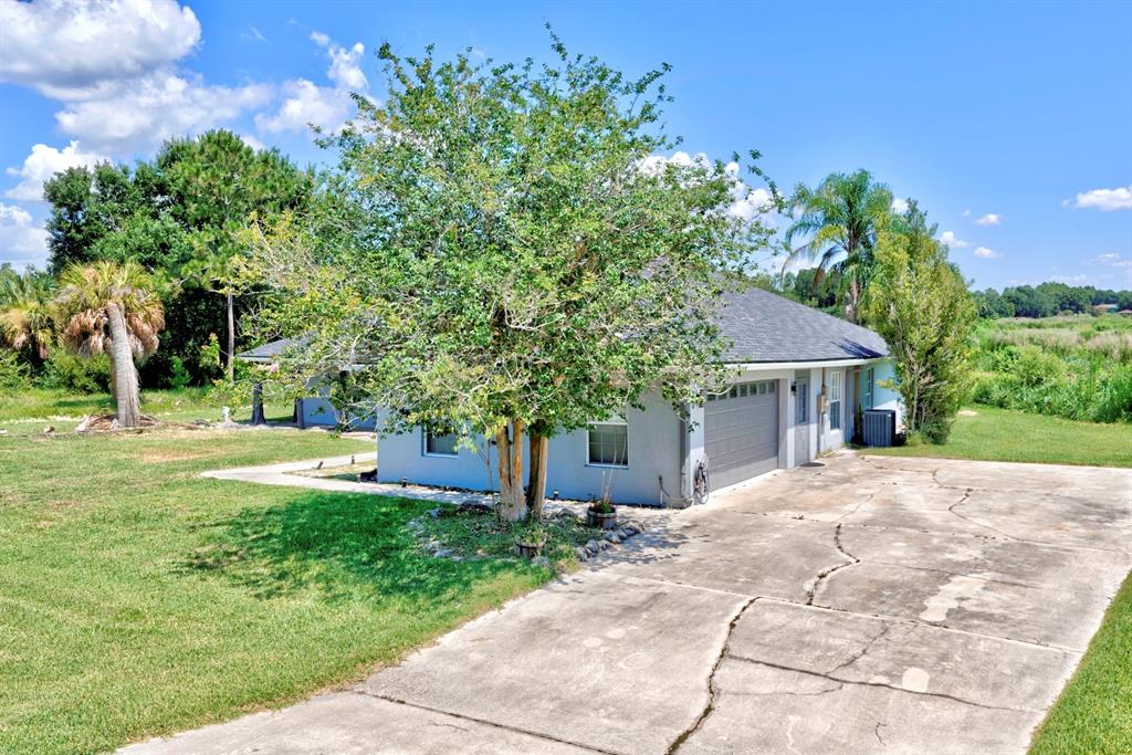 A single-story house with a gray exterior, a two-car garage, and a cracked concrete driveway — 110 GATES AVENUE, LAKE PLACID, FL