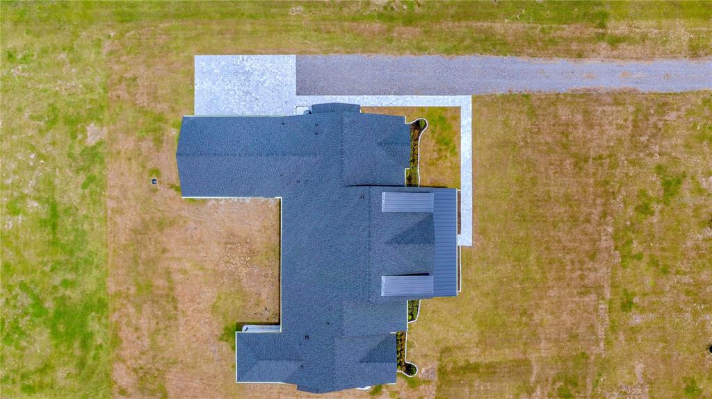 An aerial view shows a house with a dark shingled roof and a gravel driveway — 4230 TUCKER AVENUE, ST CLOUD, FL