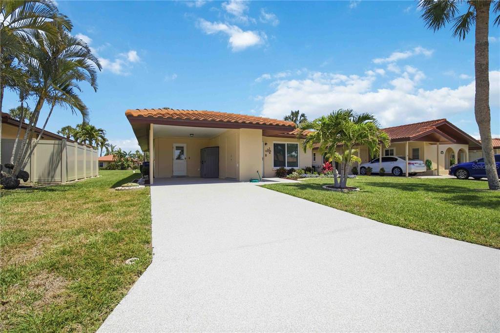A single-story house with a carport, a concrete driveway, and palm trees under a blue sky — 3303 CAMBRIDGE AVENUE, BRADENTON, FL