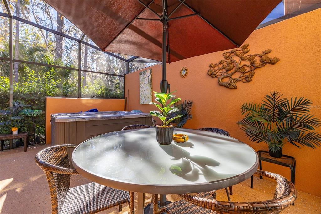 A patio with a glass-top table, wicker chairs, a hot tub, and an orange wall — 2683 CORVETTE LANE, KISSIMMEE, FL